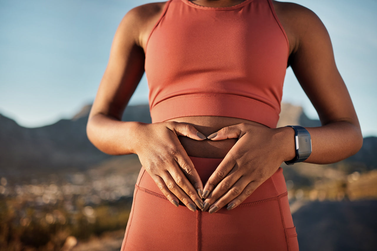 Woman in workout gear holding hands around stomach